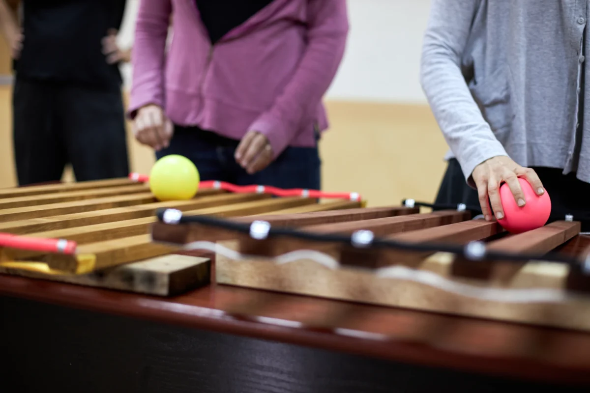 Professor aprenent tècniques de malabarisme amb una pilota purpura durant el taller de Flux de troposfera.xyz, dirigit per Dídac Gilabert, ensenyant professors a instruir estudiants.